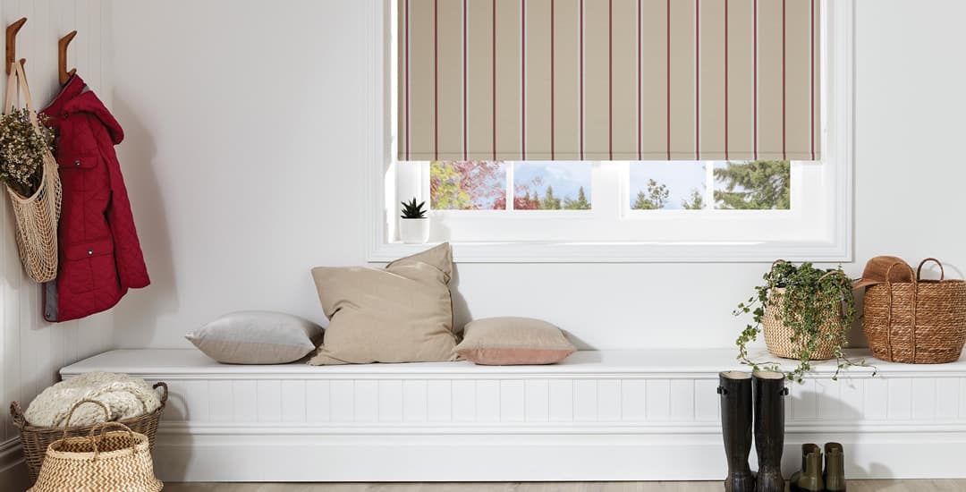 Beige and red vertical striped blackout roller blinds above window seat