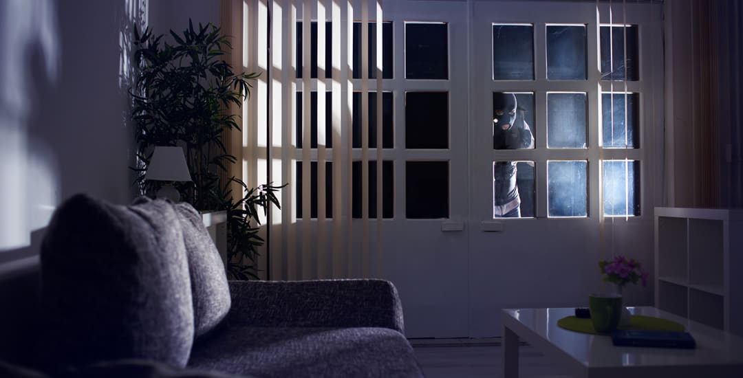 Burglar looking in window at night through vertical blinds