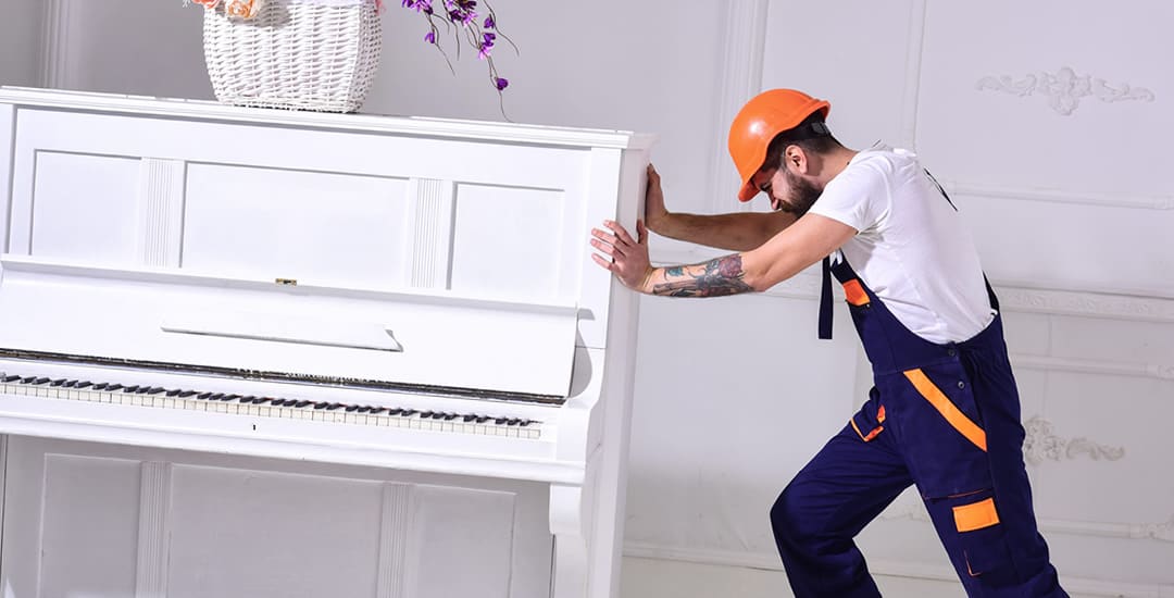 Man moving heavy piano