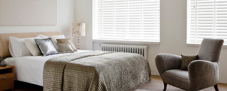 White faux wood blinds with tapes in bedroom