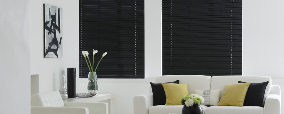 Closed black wooden blinds during daytime in living room