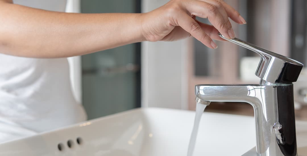 Close-up of woman’s hand turning off the water tap