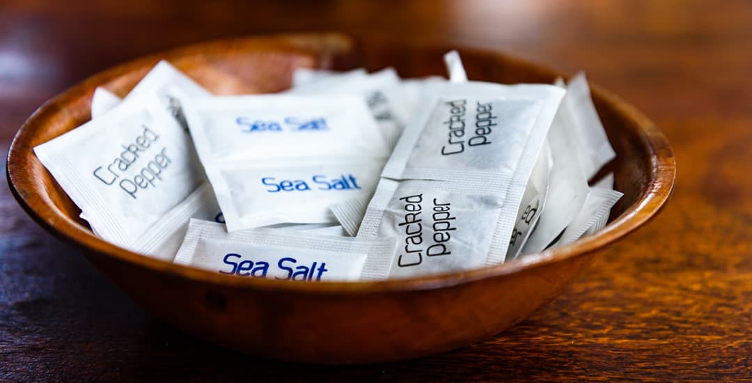 Salt and pepper sachets in a wooden bowl 