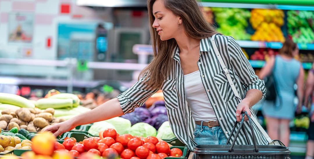 Woman with a shopping basket buying vegetables in a supermarket